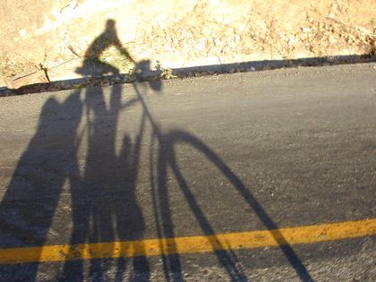 A rider's long shadow on the empty road