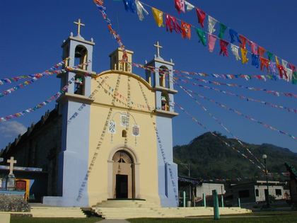 A whitewashed village church dressed in papel picado